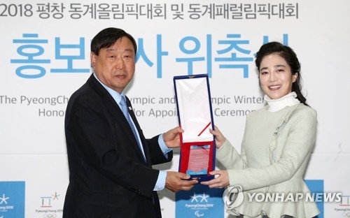 South Korean violinist Park Ji-hae (R) takes a plaque from Lee Hee-beom, head of the 2018 PyeongChang Winter Olympics organizing committee, after being named the event's honorary ambassador in a ceremony in Seoul on Nov. 6, 2017. (Yonhap)