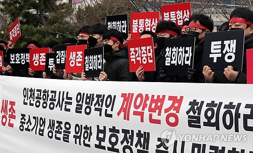 Employees of local duty-free operators hold signs near Incheon International Airport, west of Seoul, to demand a cut in rental fees on March 21, 2018. (Yonhap)