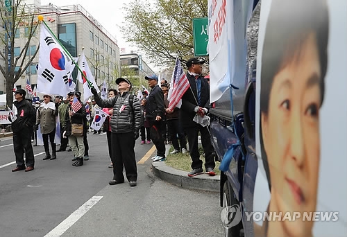 Supporters of former President Park Geun-hye wave the national flag in front of the Seoul Central District Court before Park's sentencing trial held in the afternoon of April 6, 2018. (Yonhap) 