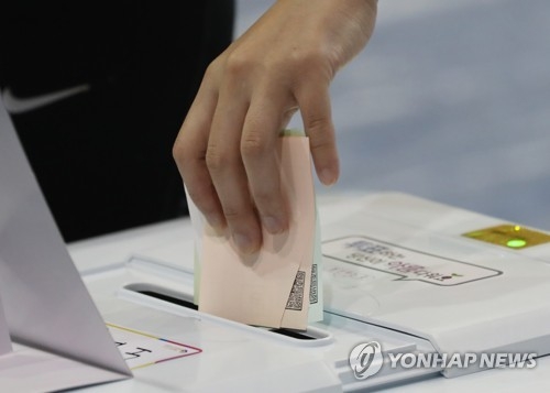 This photo taken on June 13, 2018, shows a voter putting his or her ballots into a voting box for the local elections. (Yonhap)