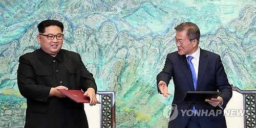 This file photo shows South Korean President Moon Jae-in (R) gesturing to North Korean leader Kim Jong-un after signing the Panmunjom Declaration at their summit talks on April 27, 2018. (Yonhap)
