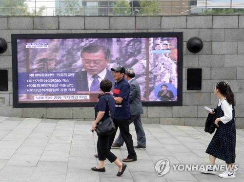 Passers-by in Gwanghwamun in central Seoul watch President Moon Jae-in announce the summit outcome with North Korean leader Kim Jong-un in Pyongyang on Sept. 19, 2018. (Yonhap) 
