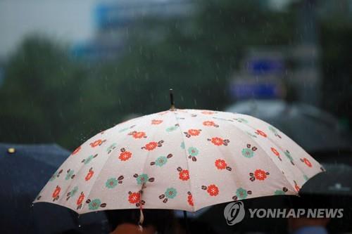The undated file photo shows pedestrians walking under umbrellas. (Yonhap)