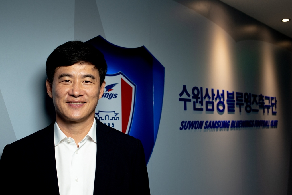 Suwon Samsung Bluewings' new head coach Park Kun-ha poses next to the K League 1 team's logo at Suwon World Cup Stadium in Suwon, 45 kilometers south of Seoul, in this photo provided by the club on Sept. 8, 2020. (PHOTO NOT FOR SALE) (Yonhap)