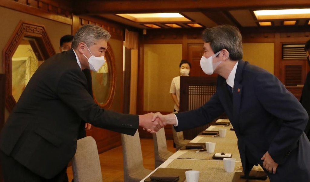 Unification Minister Lee In-young (R) shakes hands with U.S. Special Representative Sung Kim ahead of their breakfast meeting in Seoul on Aug. 24, 2021, in this photo provided by the ministry. (PHOTO NOT FOR SALE) (Yonhap)