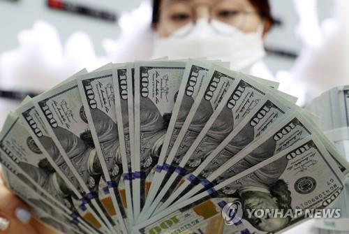 An official checks banknotes at a bank branch of Hana Bank in central Seoul, in this file photo taken March 4, 2020. (Yonhap)