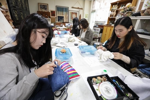 工芸文化センターで刺繍の実習を行う女子高生ら＝（聯合ニュース）