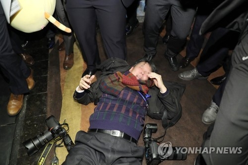暴行を受け倒れた韓国人記者＝１４日、北京（聯合ニュース）