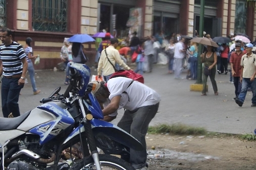 오토바이 뒤의 한 남성이 땅에 버려진 쓰레기를 뒤지고 있다.