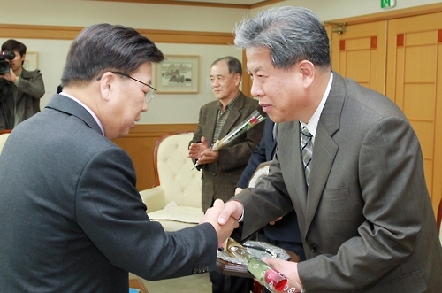 권선택 대전시장(왼쪽)이 지난해 11월 7일 오후 대전시청사에서 '공동주택 모범관리단지'로 선정된 손귀복 초록마을2단지 입주자 대표회장에게 인증패와 동판을 주고 악수하고 있다.