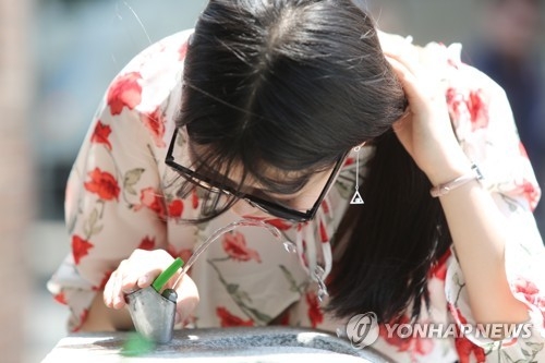 전주 한옥마을에서 물 마시는 관광객.