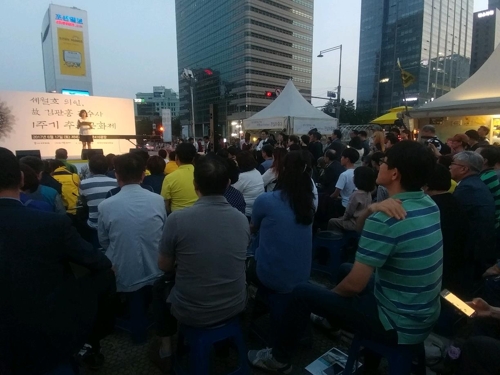 (서울=연합뉴스) 양지웅 기자 = 17일 오후 7시 서울 광화문 광장에서 열린 '고(故) 김관홍 잠수사 1주기 추모문화제'에 참석한 시민들이 고인의 부인 김혜연씨가 추도사를 경청하고 있다. 2017.6.17.yangdoo@yna.co.kr