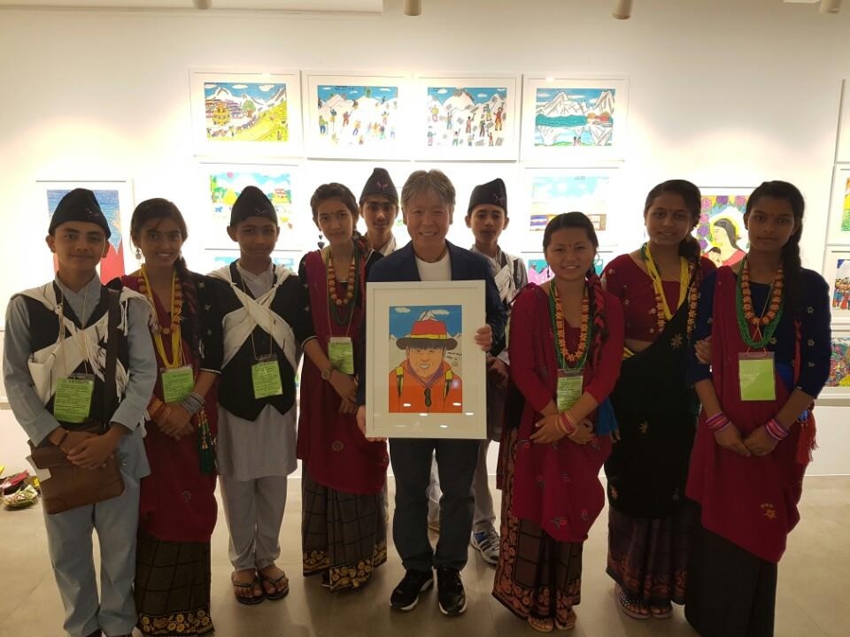 엄홍길 대장이 자신을 그린 그림을 들고 네팔 학생들과 기념촬영하고 있다. 