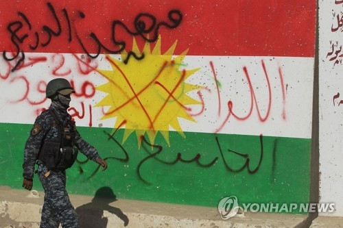 쿠르드자치정부의 깃발을 그린 벽화 앞을 지나는 이라크군[AFP=연합뉴스자료사진]