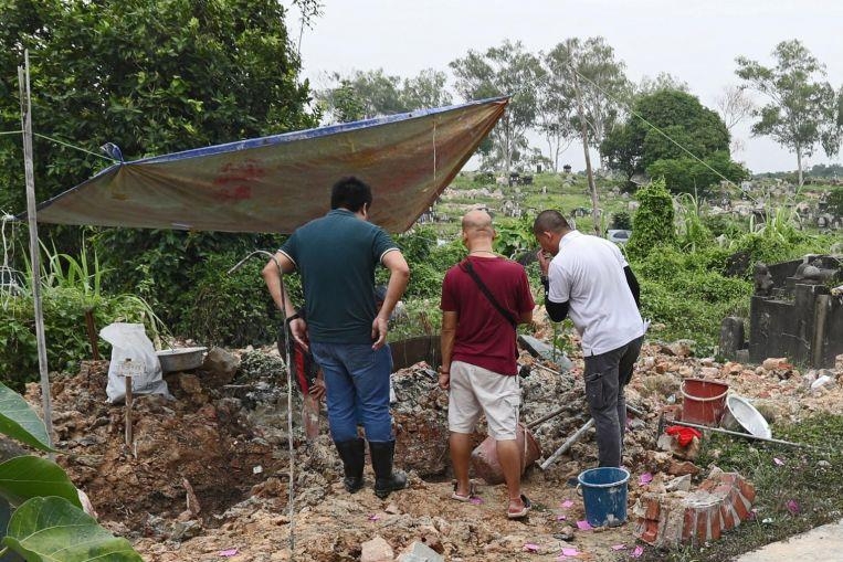 무덤 발굴 작업을 진행 중인 싱가포르 국립환경청 관계자들