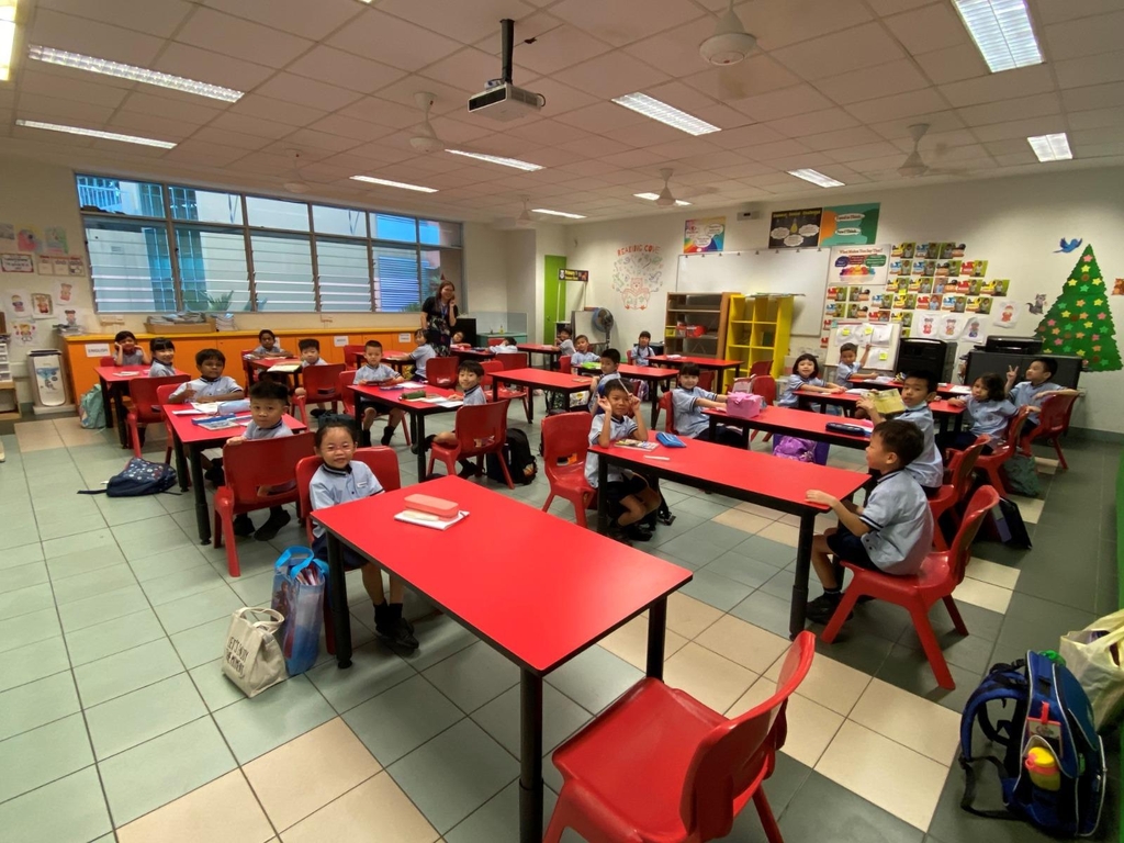 책상 양 옆으로 떨어져 앉아 수업을 받는 싱가포르 초등학생들