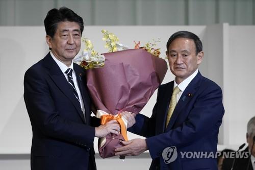 (도쿄 AP=연합뉴스) 14일 오후 일본 도쿄도의 한 호텔에서 스가 요시히데 신임 자민당 총재로부터 아베 신조(왼쪽) 총리가 꽃다발을 받고 있다. 