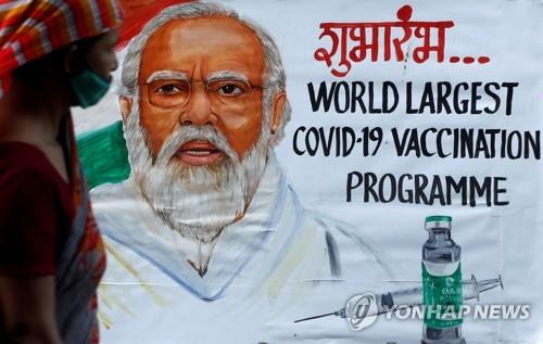 인도 뭄바이에서 나렌드라 모디 인도 총리와 코로나19 백신이 그려진 그림 앞으로 한 여성이 지나가는 모습. [로이터=연합뉴스]