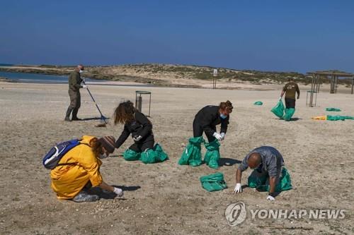 21일(현지시간) 이스라엘 항구도시 하이파의 해변에서 기름 제거 작업을 하는 자원봉사자들.[AFP=연합뉴스] 