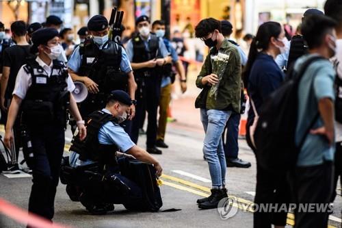 지난 2일 홍콩 코즈웨이베이에서 경찰들이 꽃을 든 남성에 대해 검문검색을 펼치는 모습. [AFP=연합뉴스]