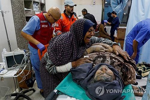 이스라엘 공격으로 부상당한 남편을 부둥켜안고 있는 팔레스타인 여성.