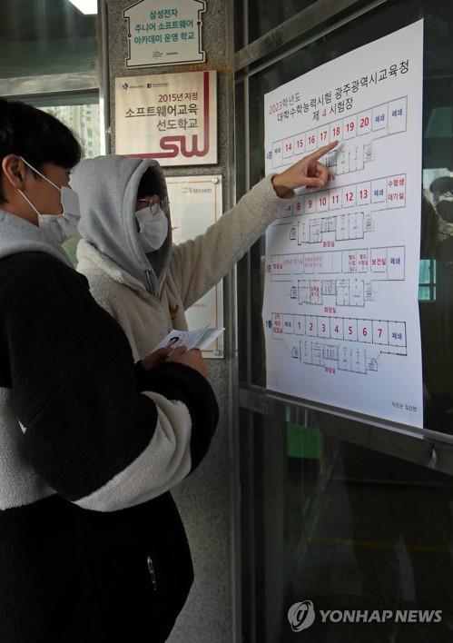 Unos aspirantes a estudiantes universitarios chequean la ubicación del sitio donde rendirán el Test de Aptitud Académica Universitaria (CSAT, según sus siglas en inglés), en una escuela de enseñanza secundaria en la ciudad suroccidental de Gwangju, el 16 de noviembre de 2022, la víspera del examen estatal para el año escolar 2023, el cual rendirán un total de 508.030 estudiantes.