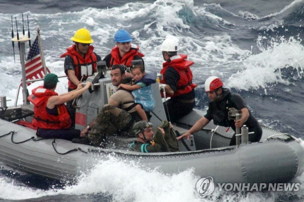6일(현지시간) 미 해군 선원들이 고열의 한살배기 아기와 가족들을 구조보트로 해군 전함에 옮기고 있다. (AP=연합뉴스)