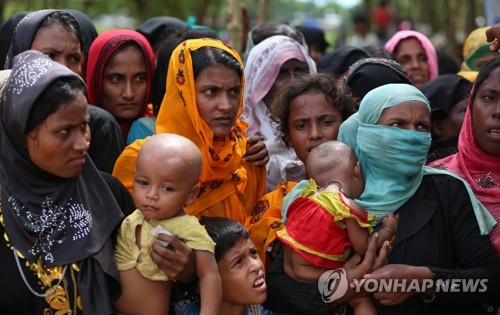 지난 5일 방글라데시 콕스 바자르의 탕칼리 난민캠프에서 로힝야 난민 여성들이 구호품을 받기 위해 어린이를 안고 줄 서 있다.[AP=연합뉴스 자료사진]