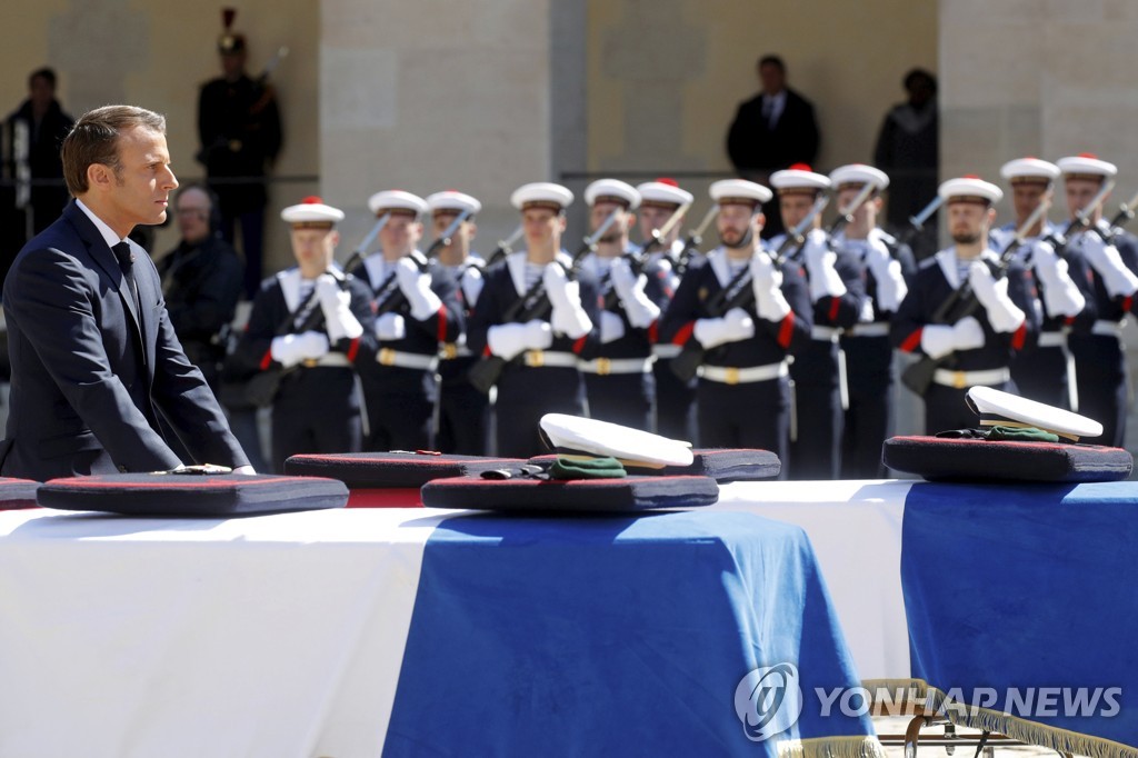 (파리 AP=연합뉴스) 14일 파리 시내 앵발리드에서 아프리카 인질구출작전 도중 전사한 두 해군 특수부대원의 장례가 엄수됐다. 사진은 에마뉘엘 마크롱 프랑스 대통령이 두 군인의 관에 예를 표하는 모습.