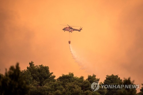 13일(현지시간) 그리스 에비아섬에서 발생한 산불을 진화하는 헬기.