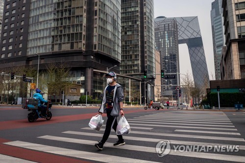 30일 베이징에서 한 남성이 마스크를 쓰고 길을 건너고 있다. [AFP=연합뉴스]