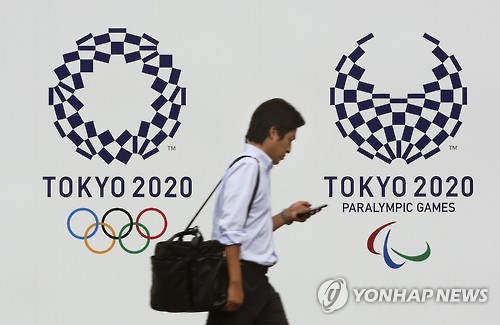 도쿄올림픽 엠블럼 앞을 지나는 시민