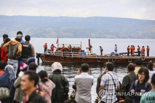 2018년 6월 22일 인도네시아 북(北) 수마트라 주 토바 호(湖)에서 유족들이 침몰한 여객선의 선체와 실종자를 찾으러 나가는 수색대원들을 바라보고 있다. [EPA=연합뉴스자료사진]