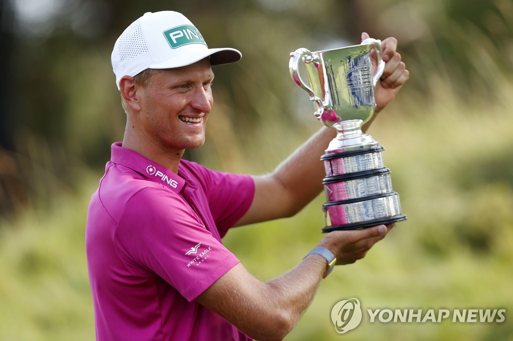 In this EPA file photo from Dec. 4, 2022, Adrian Meronk of Poland hoists the champion's trophy after winning the ISPS Handa Australian Open at the Victoria Golf Club in Melbourne. (Yonhap)