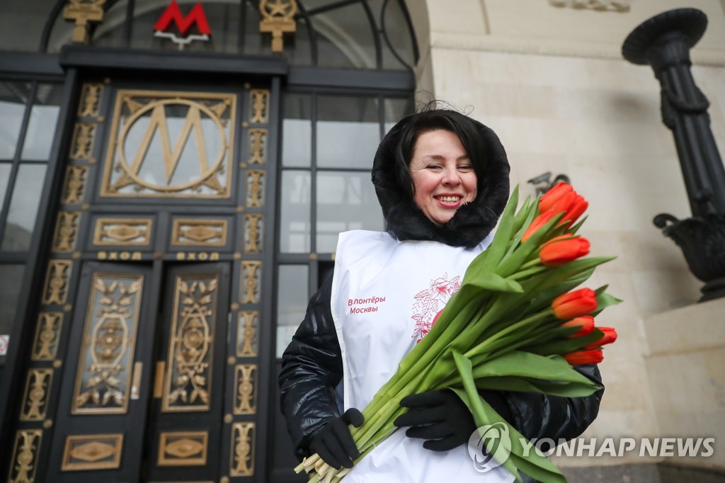 (타스=연합뉴스) 8일(현지시간) 모스크바 시내 지하철 역사 앞에서 여성들에게 꽃을 나누어주는 여당 '통합러시아당' 자원 봉사자.