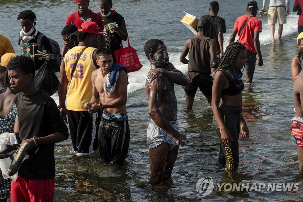 미국행을 원하는 중남미 난민들이 텍사스주와 멕시코의 국경에 있는 리오그란데 강에서 16일 목욕을 하고 있다. [로이터=연합뉴스]