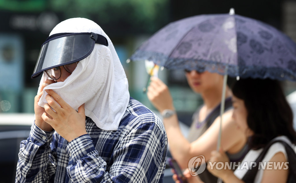 서울 광화문광장에서 한 시민이 수건으로 햇빛을 가리고 있다. <<연합뉴스DB>>