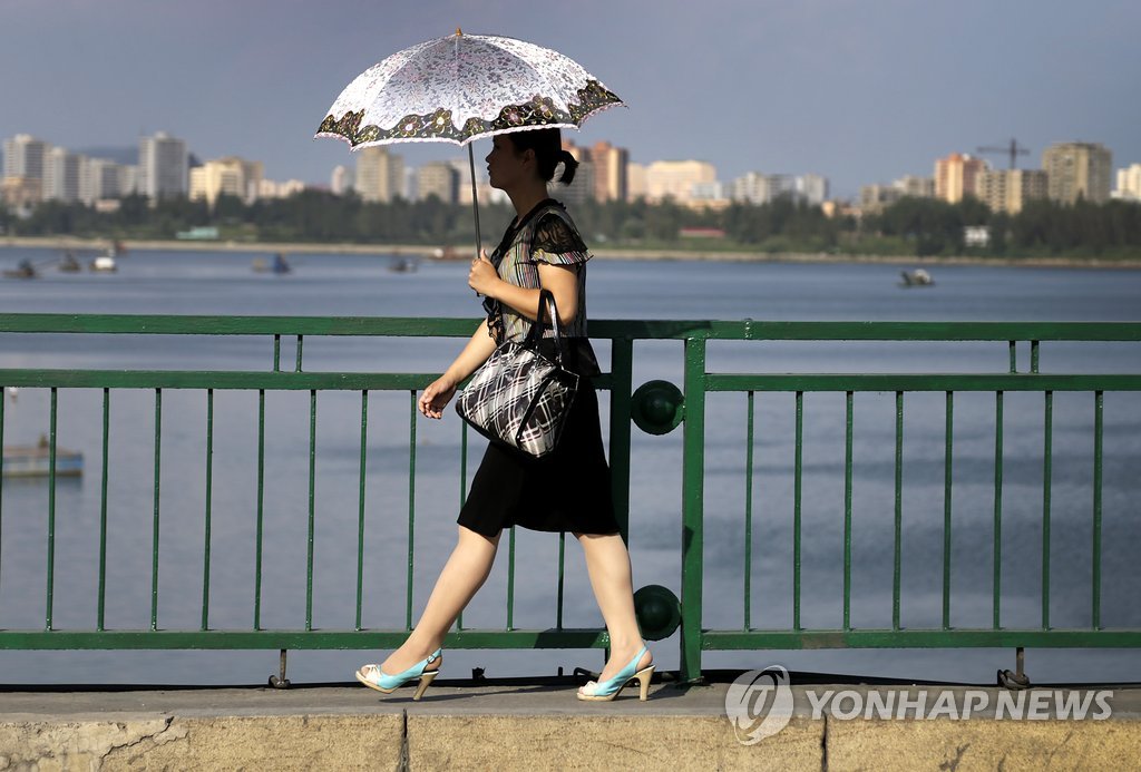 지난 8월 30일 북한 평양에서 한 여성이 양산을 쓰고 대동강변을 걸어가고 있다. (AP=연합뉴스 자료사진)