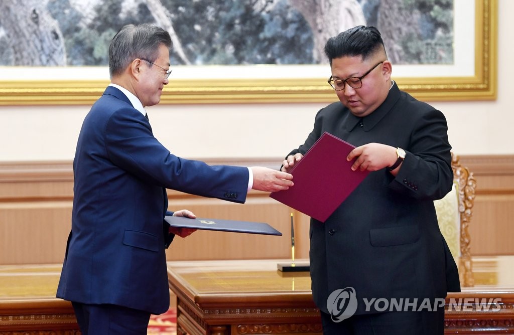 South Korean President Moon Jae-in (L) and North Korean leader Kim Jong-un exchange copies of their signed summit agreement at Paekhwawon State Guesthouse in Pyongyang on Sept. 19, 2018. In the agreement, signed after two rounds of talks between the two leaders, Kim reaffirmed his commitment to a nuclear-free Korean Peninsula and promised to visit Seoul "in the near future." (Pool photo) (Yonhap)