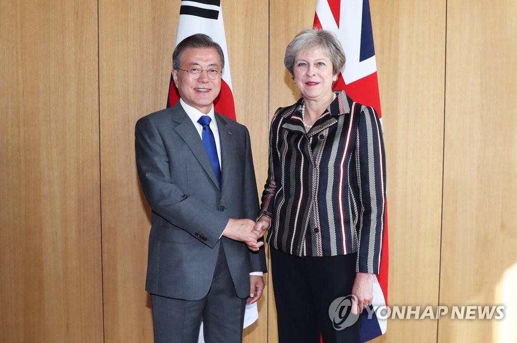 South Korean President Moon Jae-in (L) and British Prime Minister Theresa May shake hands before the start of their bilateral summit held on the sidelines of the Asia-Europe Meeting in Brussels on Oct. 19, 2018. (Yonhap)