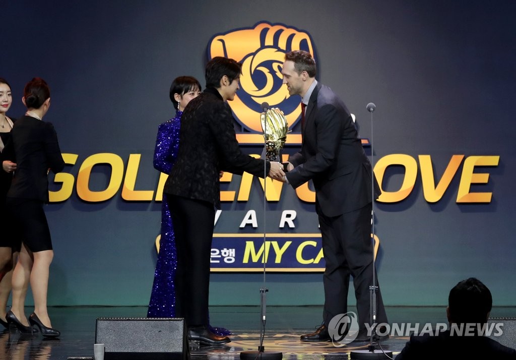 Josh Lindblom (R), formerly of the Doosan Bears in the Korea Baseball Organization, receives the Golden Glove in the pitcher category during the annual awards ceremony at COEX in Seoul on Dec. 9, 2019. (Yonhap)