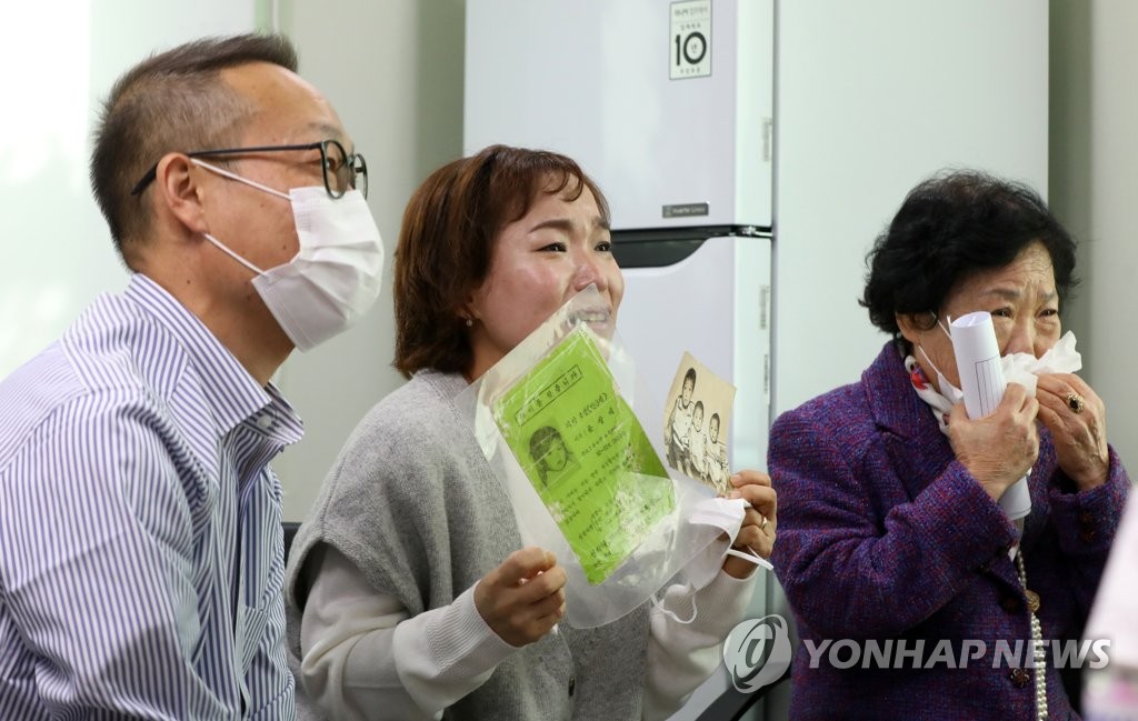 Yoon Sang-hee (C), twin sister of Yoon Sang-ae, a Korean-born adoptee who is now an American citizen, holds a photo and a poster during a reunion held via a video call in Seoul on Oct. 15, 2020, 44 years after the younger Yoon went missing. Next to Yoon is their older brother Yoon Sang-myung (L) and mother Lee Eung-soon. (Yonhap) 