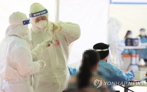 Medical workers carry out new coronavirus tests on visitors at a makeshift clinic in Siheung, southwest of Seoul, on Oct. 20, 2020. (Yonhap)