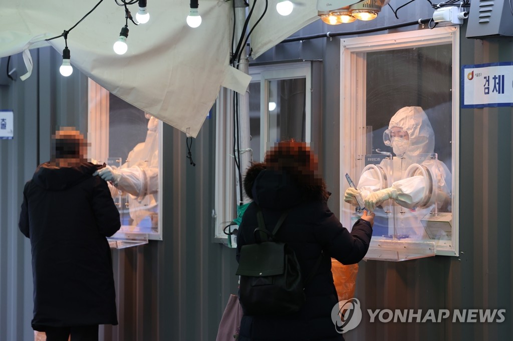 Medical workers collect specimens for coronavirus testing at a makeshift clinic in front of Seoul Station on Jan. 11, 2021. (Yonhap)