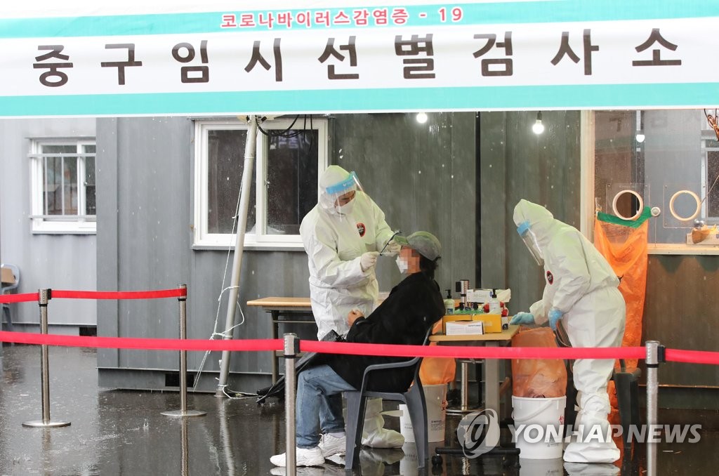 Health workers conduct a new coronavirus test on a citizen at a temporary testing site in front of Seoul Station in central Seoul on March 1, 2021. (Yonhap)