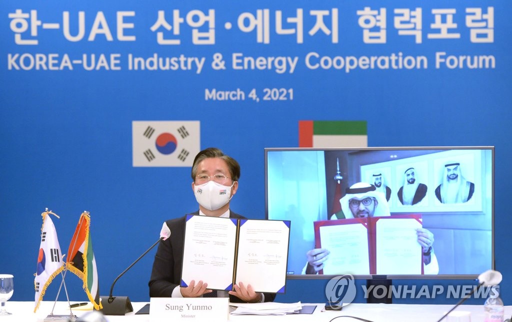 Trade, Industry and Energy Minister Sung Yun-mo (L) and United Arab Emirates Minister of Industry and Advanced Technology Sultan Ahmed Al Jaber show a memorandum of understanding on cooperation on hydrogen economy and industrial technologies during the Korea-UAE Industry and Energy Cooperation Forum held online on March 4, 2021, in this photo provided by the Ministry of Trade, Industry and Energy. (PHOTO NOT FOR SALE) (Yonhap)