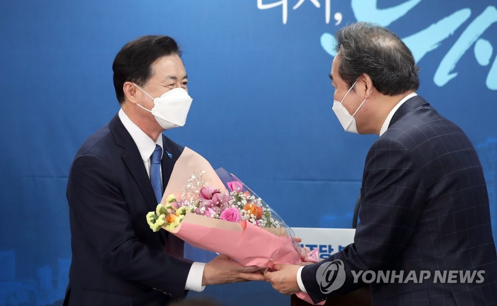 Former Oceans Minister Kim Young-choon (L) receives a bouquet of flowers from Democratic Party (DP) Chairman Lee Nak-yon in Busan, 450 kilometers southeast of Seoul, on March 6, 2021, after being named the DP's candidate for Busan mayoral by-election. (Yonhap)