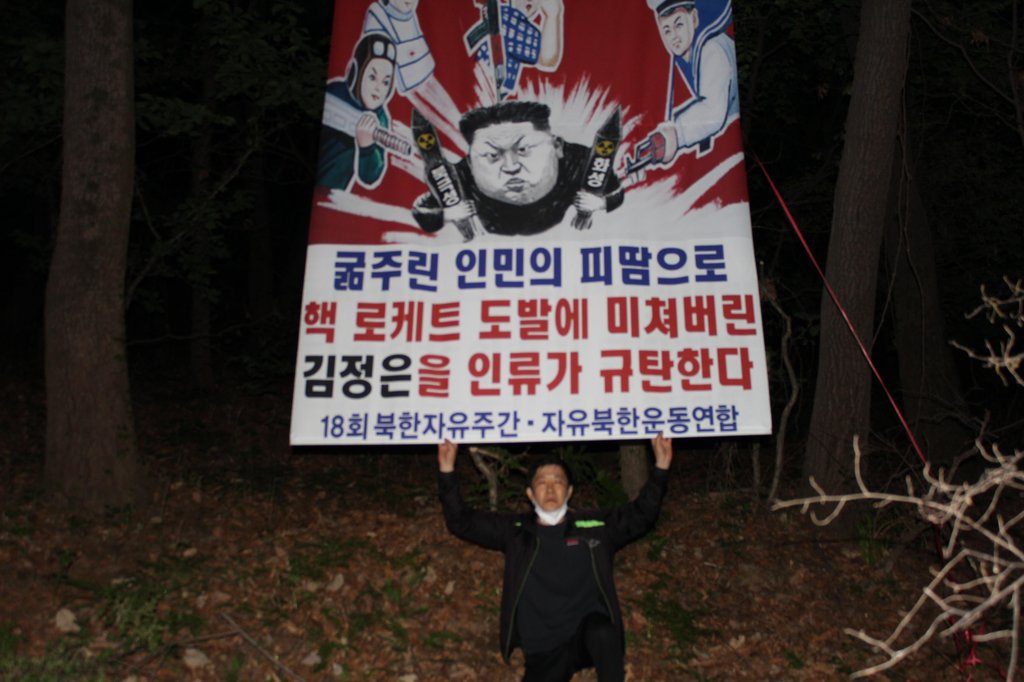 This photo, provided by Fighters for a Free North Korea, shows its leader Park Sang-hak holding up a poster condemning North Korean leader Kim Jong-un. (PHOTO NOT FOR SALE) (Yonhap)