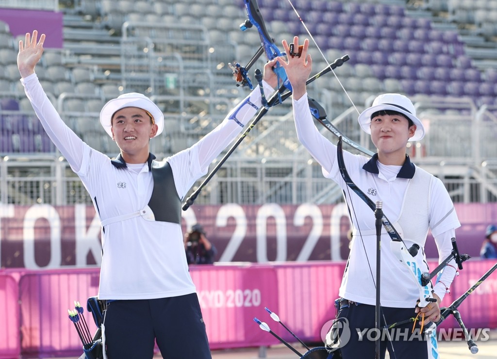 South Korean archer Kim Je-deok (L) celebrates with his teammate An San after winning the gold medal in the mixed team event at the Tokyo Olympics at Yumenoshima Park Archery Field in Tokyo on July 24, 2021. (Yonhap)