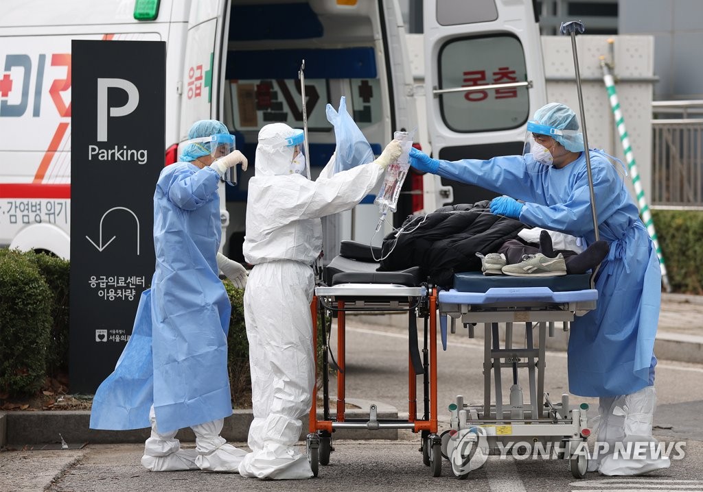 Medical workers transport a COVID-19 patient from an ambulance at Seoul Medical Center in Seoul on March 25, 2022. (Yonhap)
